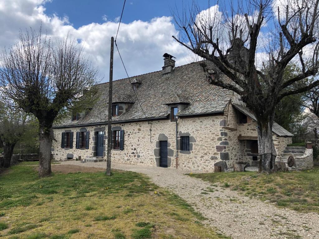ein altes Steinhaus mit Bäumen davor in der Unterkunft Maison typique Auvergnate, piscine et four à pain in Saint-Christophe-les-Gorges