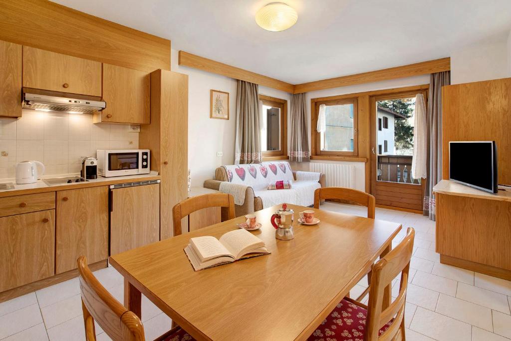 a kitchen and dining room with a wooden table and a kitchen and a living room at Baita al Pian Ginepro in Bormio