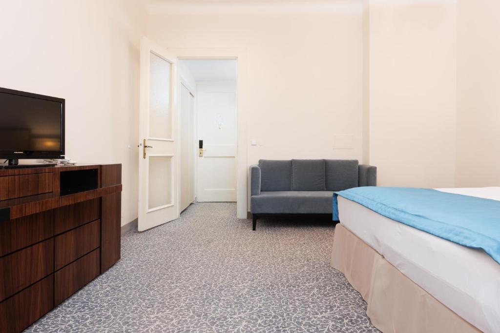 a bedroom with a bed and a tv and a chair at OREA Spa Hotel Bohemia Mariánské Lázně in Mariánské Lázně