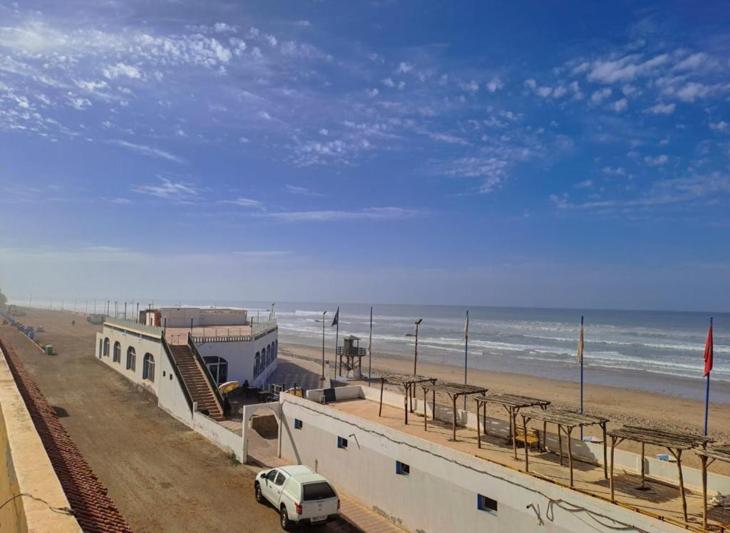 a white van parked on a beach next to the ocean at Apartamentos EL BARCO in Sidi Ifni