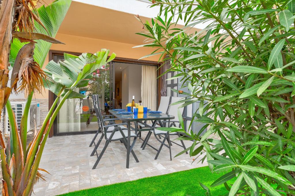 una mesa y sillas en un patio con plantas en Brand new apartment in Park Albatros with pool view, en San Miguel de Abona