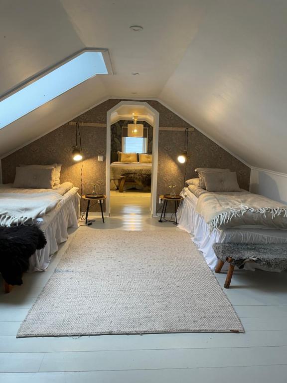 a attic room with three beds and a mirror at Ruth & Iris Cottage in Nässjö