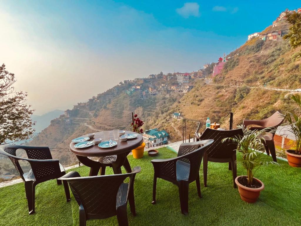 a table and chairs with a view of a mountain at Vanshika homes Near mall road in Kasauli