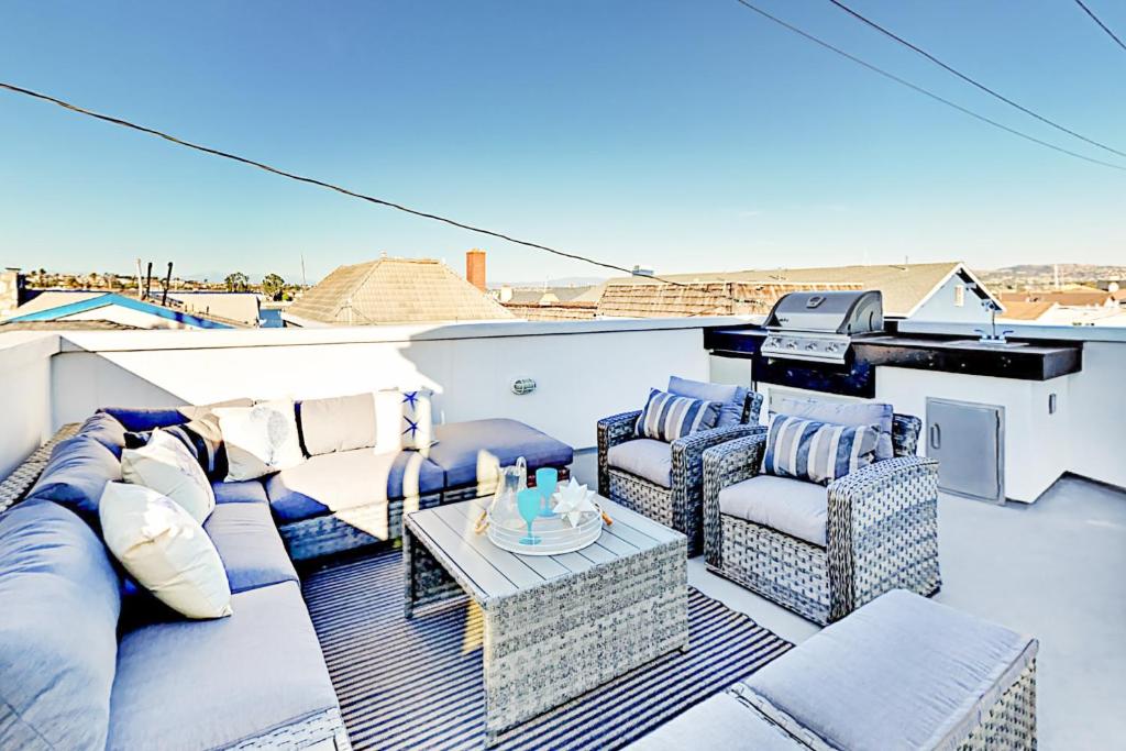 un patio con sofás y una mesa en el techo en Luxe Balboa Peninsula Condo w Gourmet Kitchen and Epic Rooftop Deck, en Newport Beach