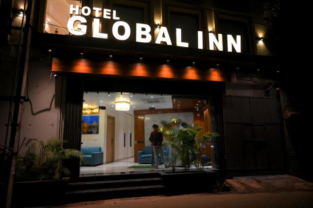 a man standing outside of a hotel global inn at night at Hotel Global Inn by T&G in Amritsar