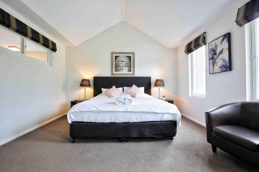 Central Hobart - Beautiful Apartment في هوبارت: غرفة نوم بسرير كبير وكرسي
