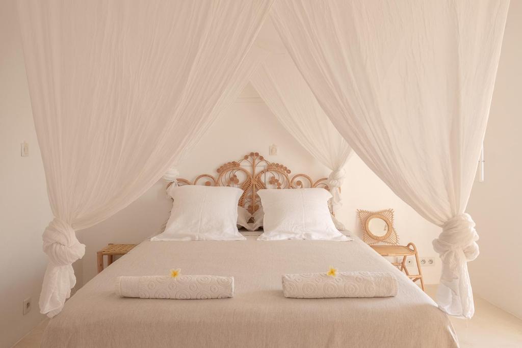 a white bed with two white pillows and a canopy at La Kazaka Terre Sainte in Saint-Pierre