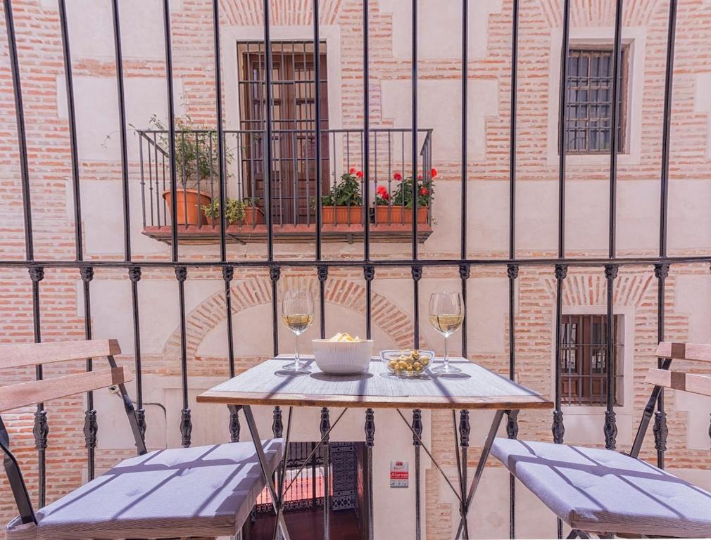 マラガにある-MalagaSunApts- Vibrant Historic City Centreのテーブル(椅子2脚付)とワイン2杯
