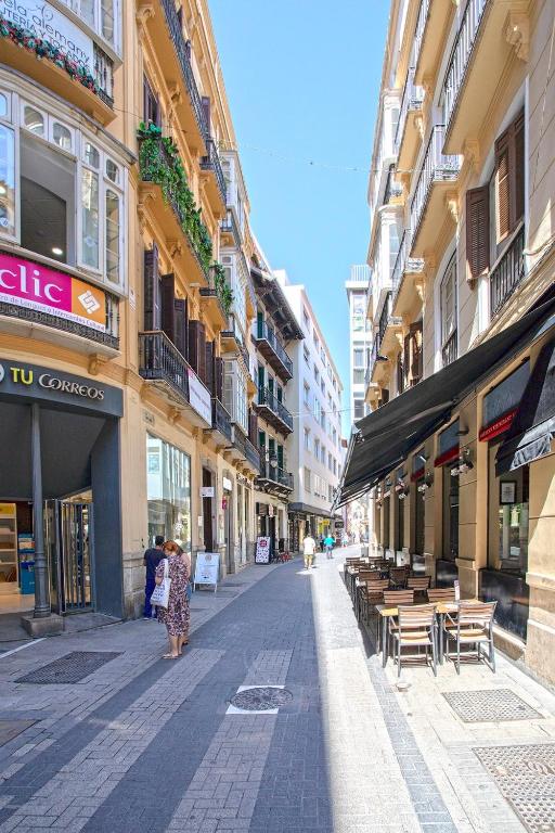 kobieta idąca ulicą miasta z budynkami w obiekcie -MalagaSunApts- Historic Heart of Malaga AA WIFI w Maladze