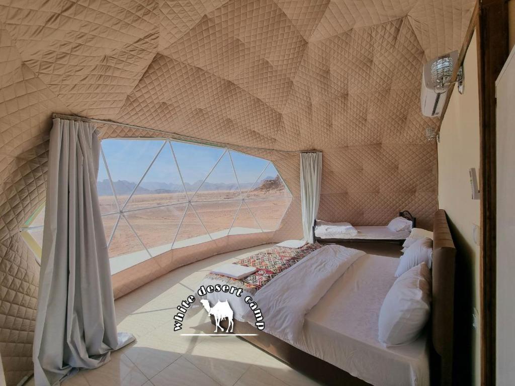 Cama en habitación con ventana grande en White Desert Camp, en Wadi Rum