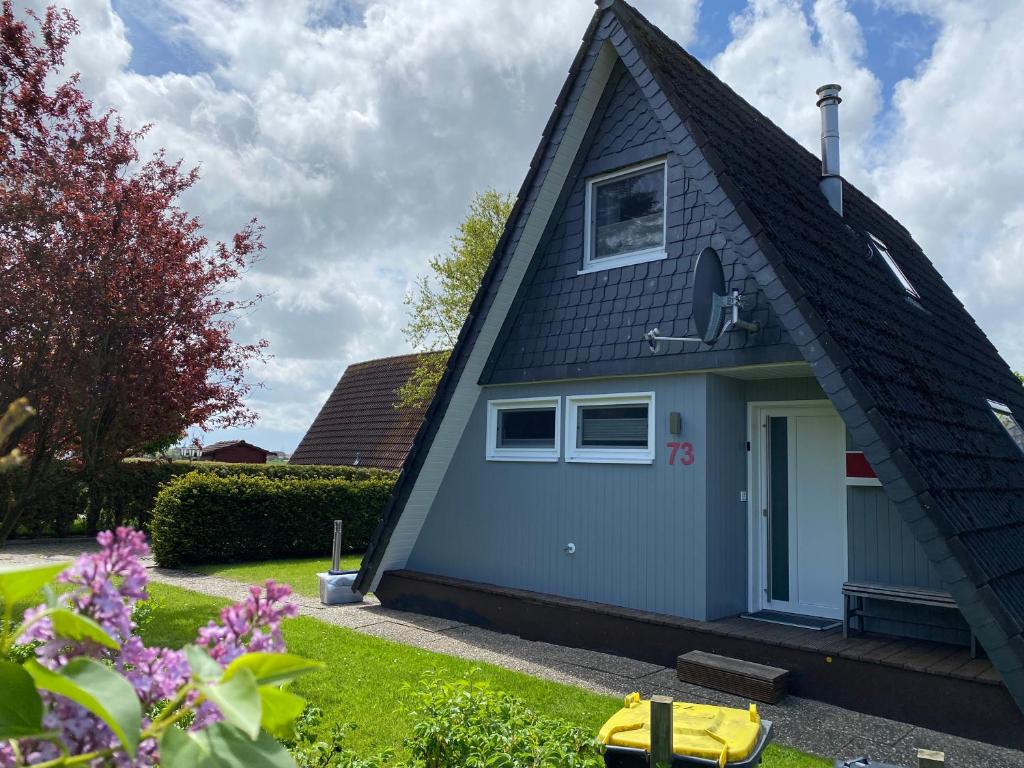 ein blaues Haus mit einem Gamer-Dach in der Unterkunft Murmel 1 - Strandkorb, Wallbox, WLan, Kamin in Carolinensiel