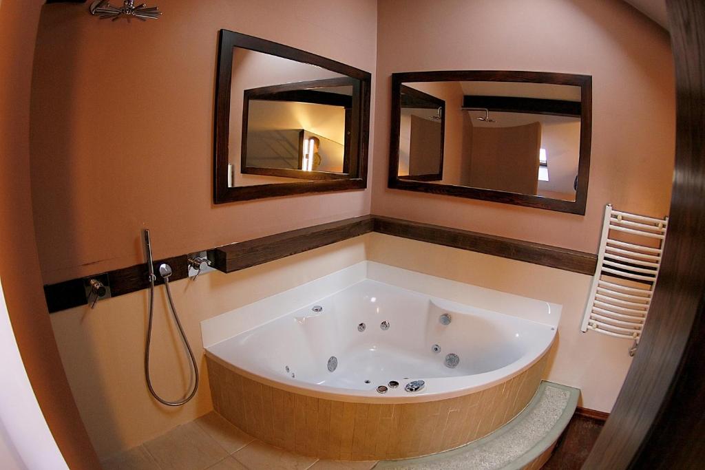 y baño con bañera grande y 2 espejos. en Krakow Jacuzzi Apartment, en Cracovia