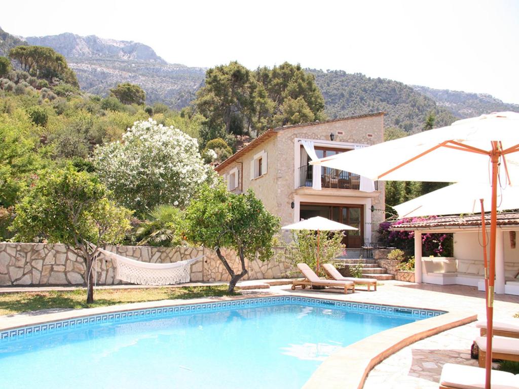 uma piscina com um guarda-sol e uma casa em Cas Puput em Sóller