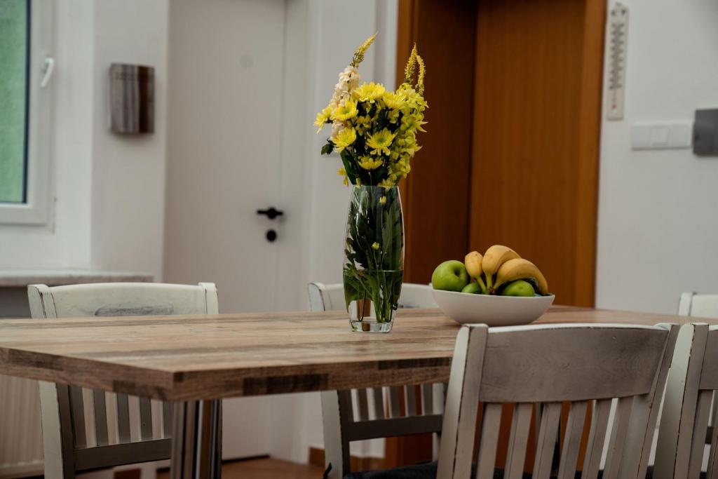 einen Tisch mit einer Vase Blumen und einer Schale Obst in der Unterkunft Bessemer in Wien