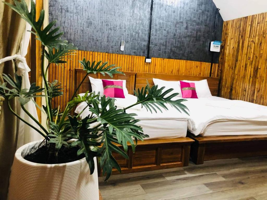 Schlafzimmer mit einem Bett mit rosa Kissen und Pflanzen in der Unterkunft กอบสุข รีสอร์ท 2 k14 