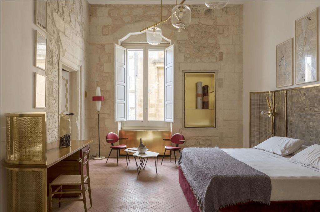 una camera con letto, scrivania e sedie di Palazzo Luce a Lecce