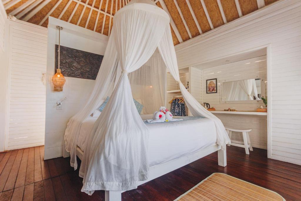 a bedroom with a bed with a mosquito net at Shrining Cottages Lembongan in Nusa Lembongan