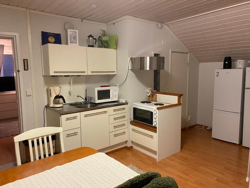 uma pequena cozinha com armários brancos e um frigorífico branco em Koskentien kotimajoitus em Jämsä