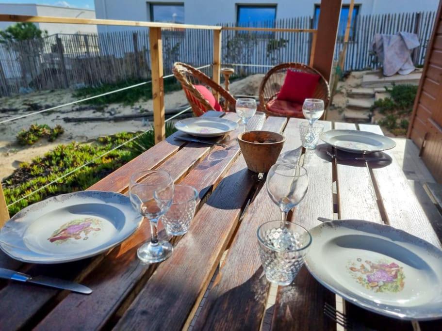 une table en bois avec des assiettes et des verres à vin dessus dans l'établissement La Cabane de Chantovan ~ 300m de l'océan, à Mimizan