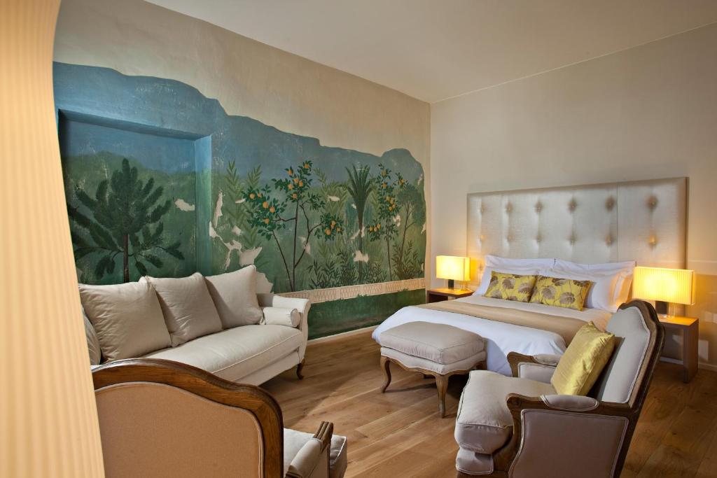 SiranにあるChâteau De Siran - Hôtel & Spaのベッドルーム1室(ベッド1台付)が備わります。壁には大きな絵画が飾られています。