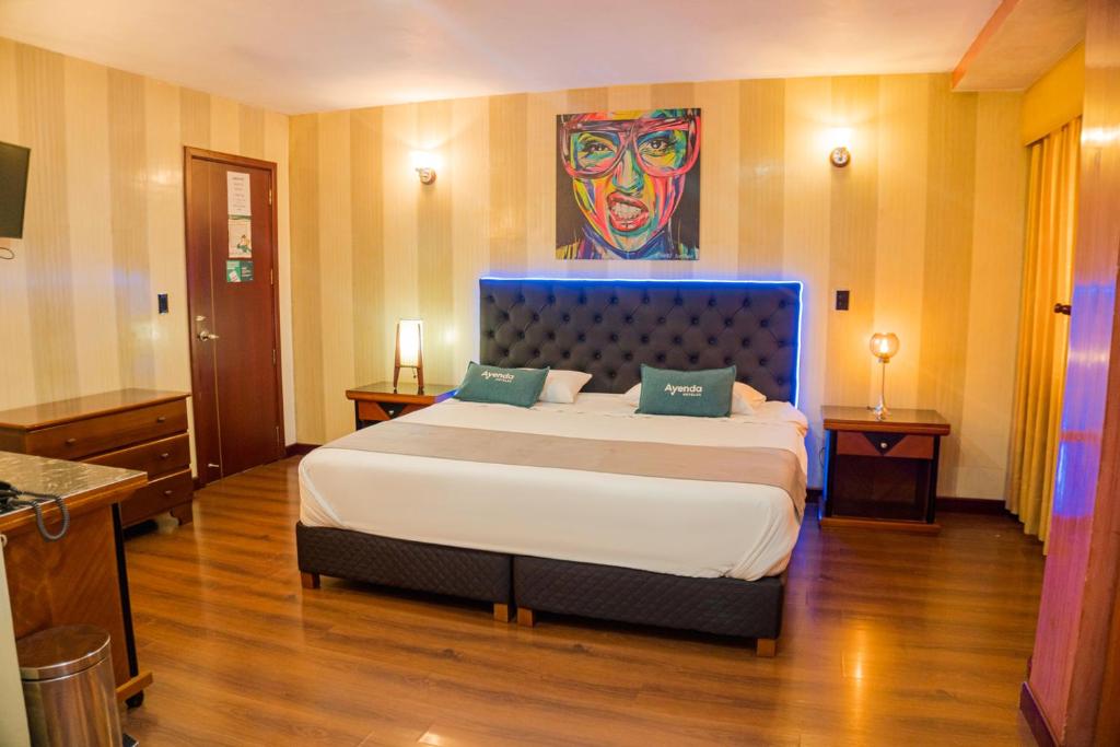 una camera da letto con un grande letto e un dipinto sul muro di Ayenda Imperio Real a Pereira