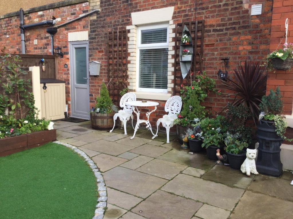 a patio with two chairs and a table and some plants at Leafy Lytham central Lovely ground floor 1 bedroom apartment with private garden In Lytham dog friendly in Lytham St Annes