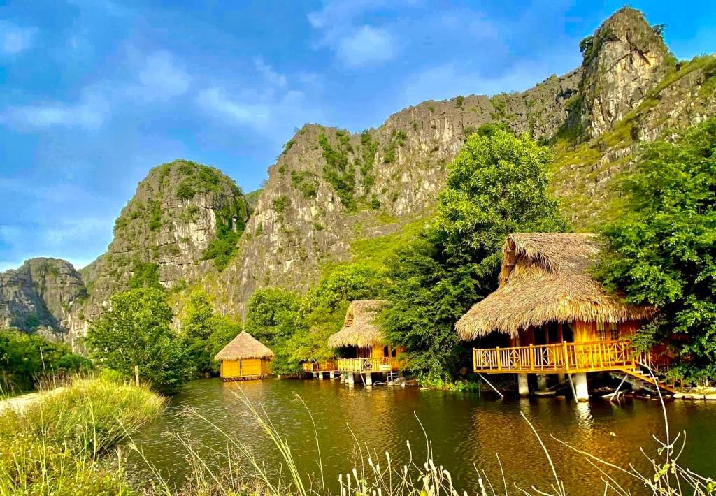 a village on the water with mountains in the background at Hang Lan Bungalow in Ninh Binh