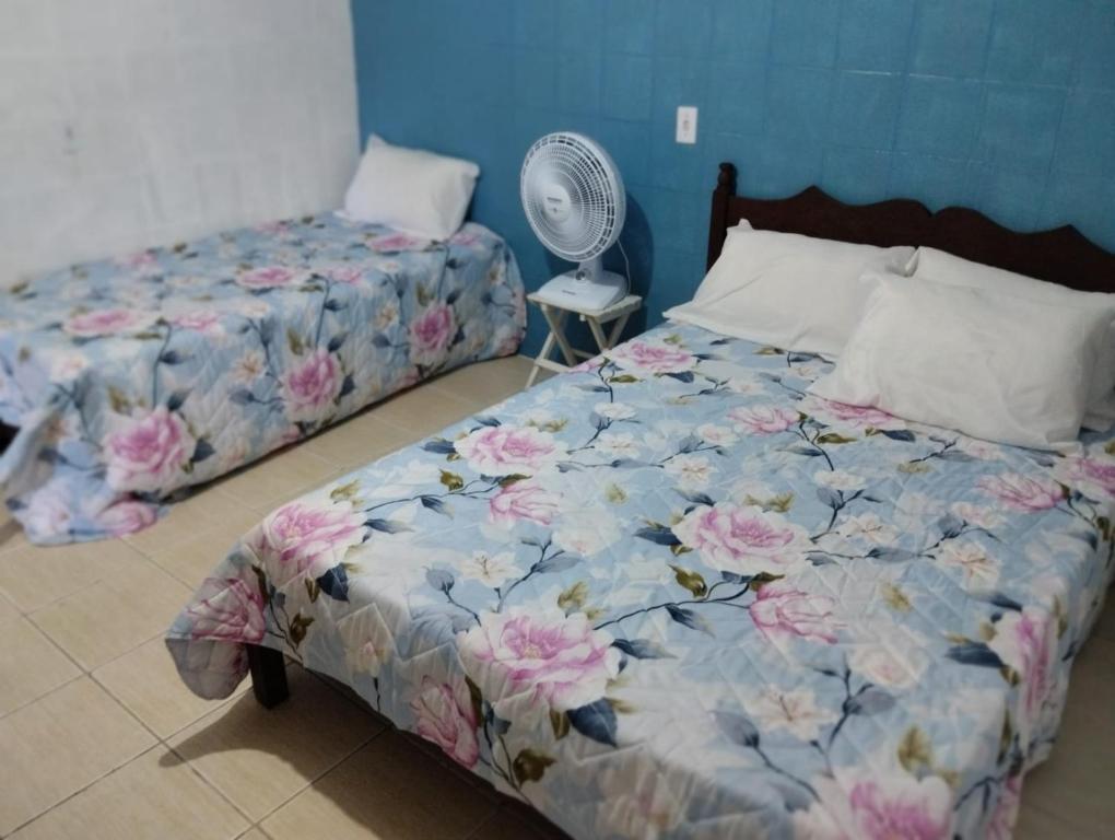 a bedroom with two beds and a fan at Apartamento cercado por natureza e diversão in Maceió