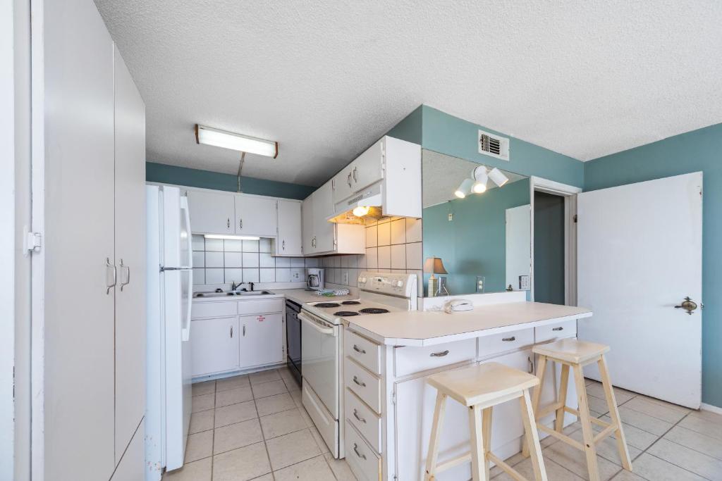 a kitchen with white cabinets and blue walls and stools at Summit Beach Resort 1412 in Panama City Beach