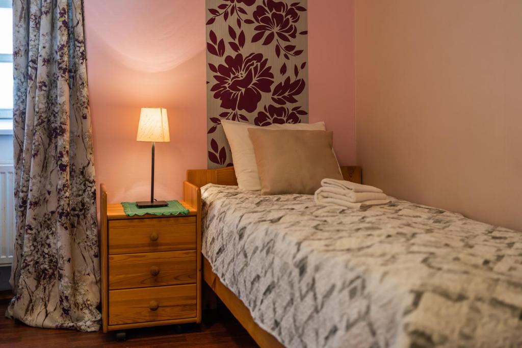 a bedroom with a bed and a lamp on a dresser at Püha Vaimu külalistemaja in Tallinn