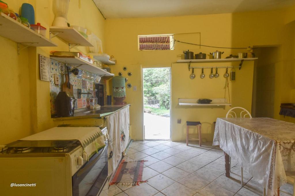 a kitchen with yellow walls and a table in it at Quinca’s Hostel in Lençóis