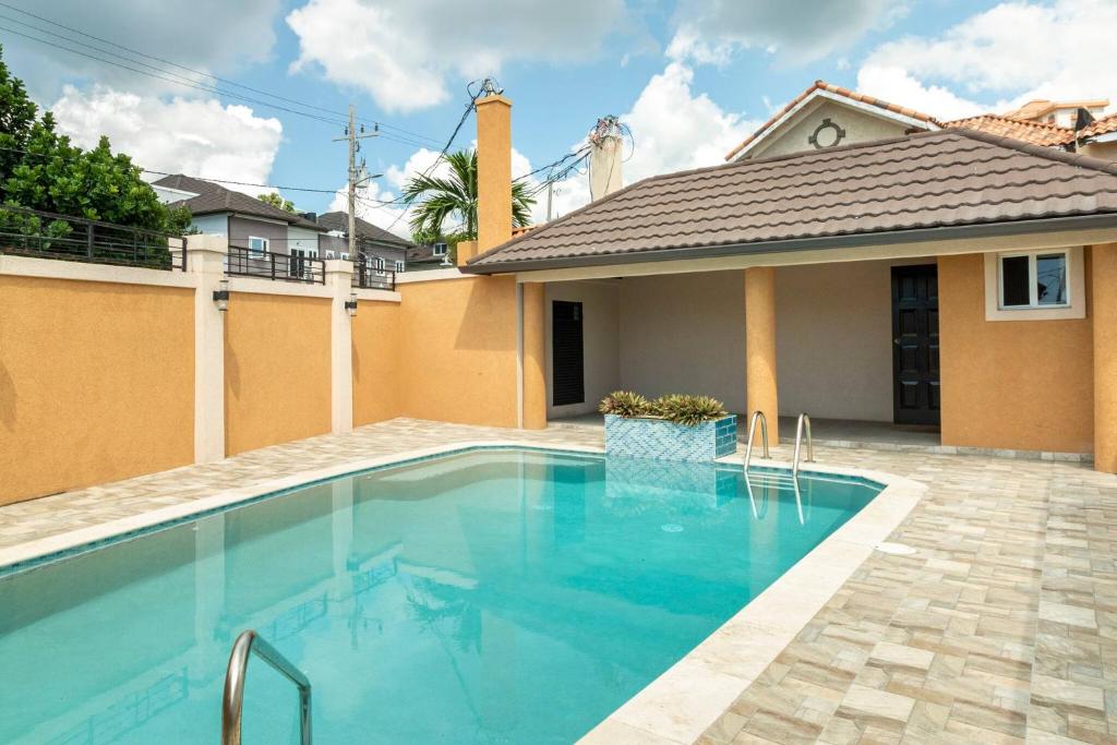 a swimming pool in front of a house at Brand New Pool Manor Park with WIFI centrally-located in Kingston