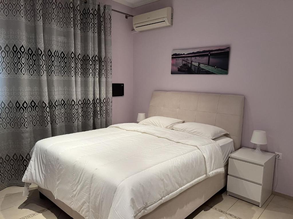 a bedroom with a white bed and a curtain at Piraeus Cozy in Piraeus