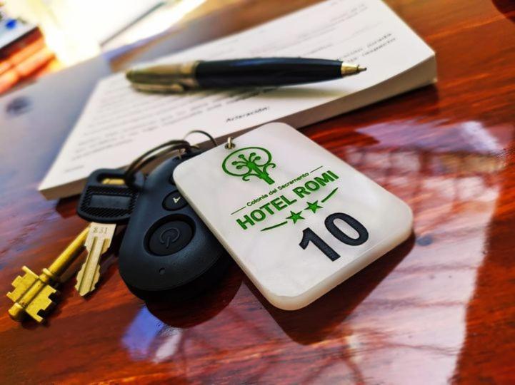 a key chain on a table with a pen and papers at Hotel Romi in Colonia del Sacramento