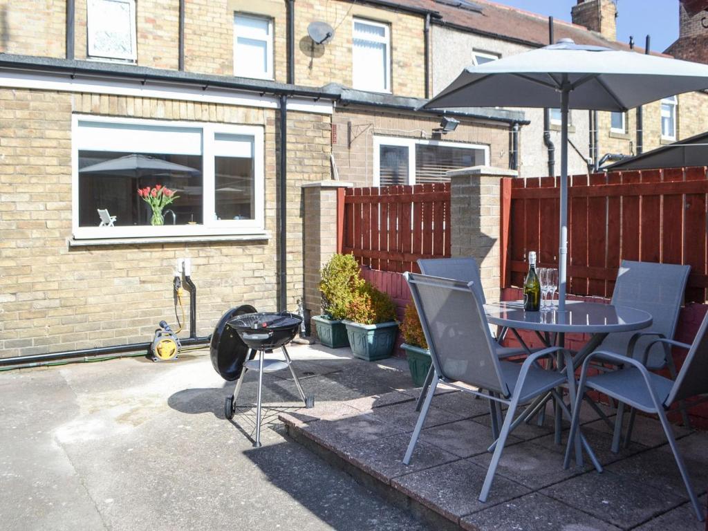a patio with a table and chairs and an umbrella at Seaside Retreat in Amble