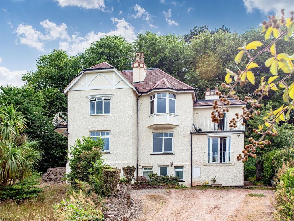 a large white house on a hill with trees at Westerlands Apartment in Torquay