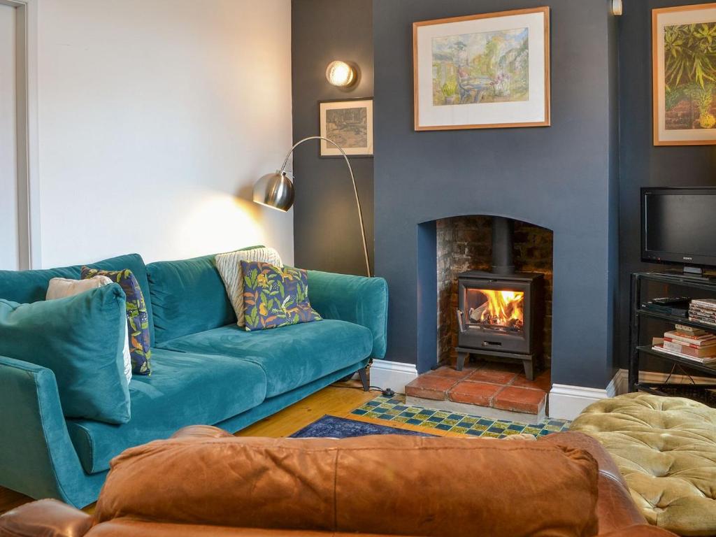 sala de estar con sofá azul y chimenea en Fox Cottage en Beverley