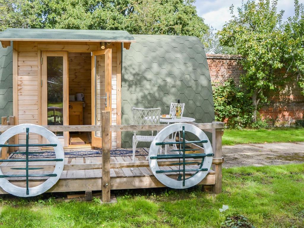 a tiny house with a deck with a table and chairs at The Squirrels strelley Barn in Woodham Mortimer