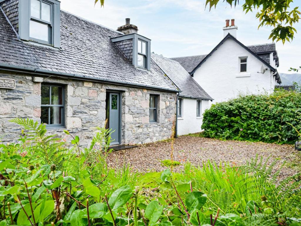 a cottage with a garden in front of it at Oakwood Cottage in Glencoe