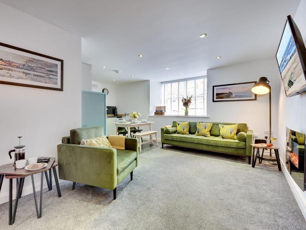 a living room with two green couches and a table at Heron Apartment in Berwick-Upon-Tweed