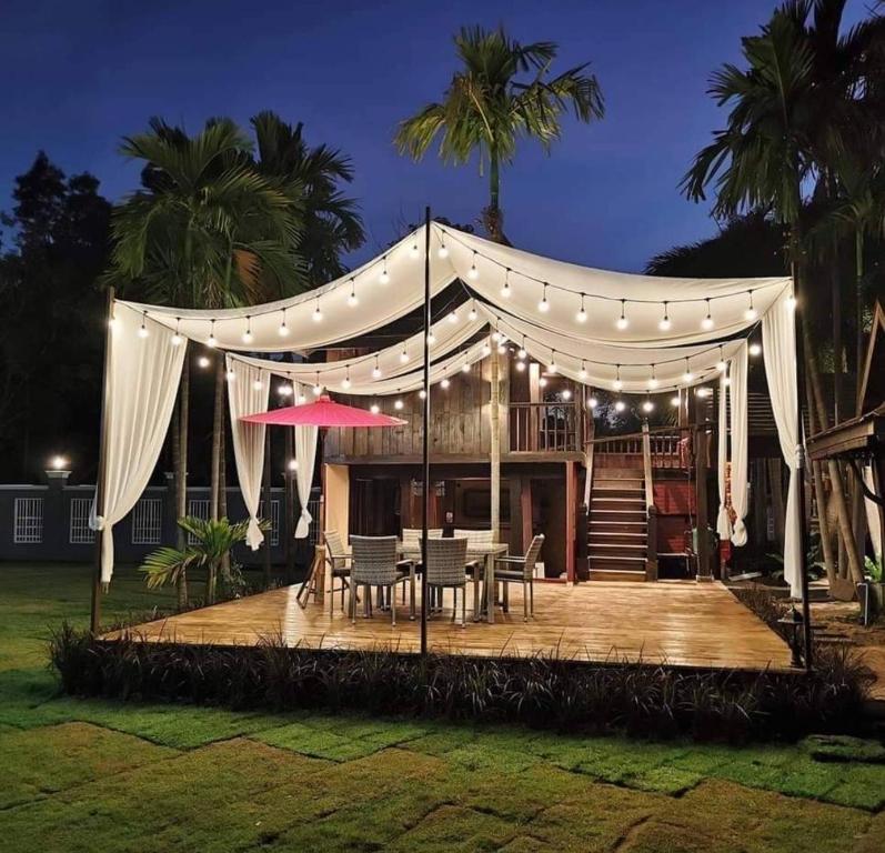 a tent with a table and chairs on a deck at night at HOMETHAI RESORT (โฮมไทยรีสอร์ท) 