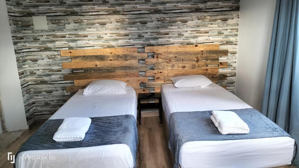 two beds in a room with a brick wall at Garden Place Alojamento Local in Viseu
