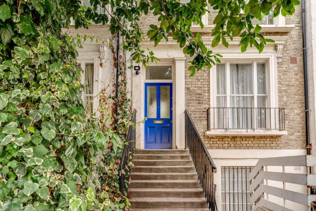 a blue door on a brick house with stairs at Bright Two Bedroom Apartment Near Vibrant Camden Town in London
