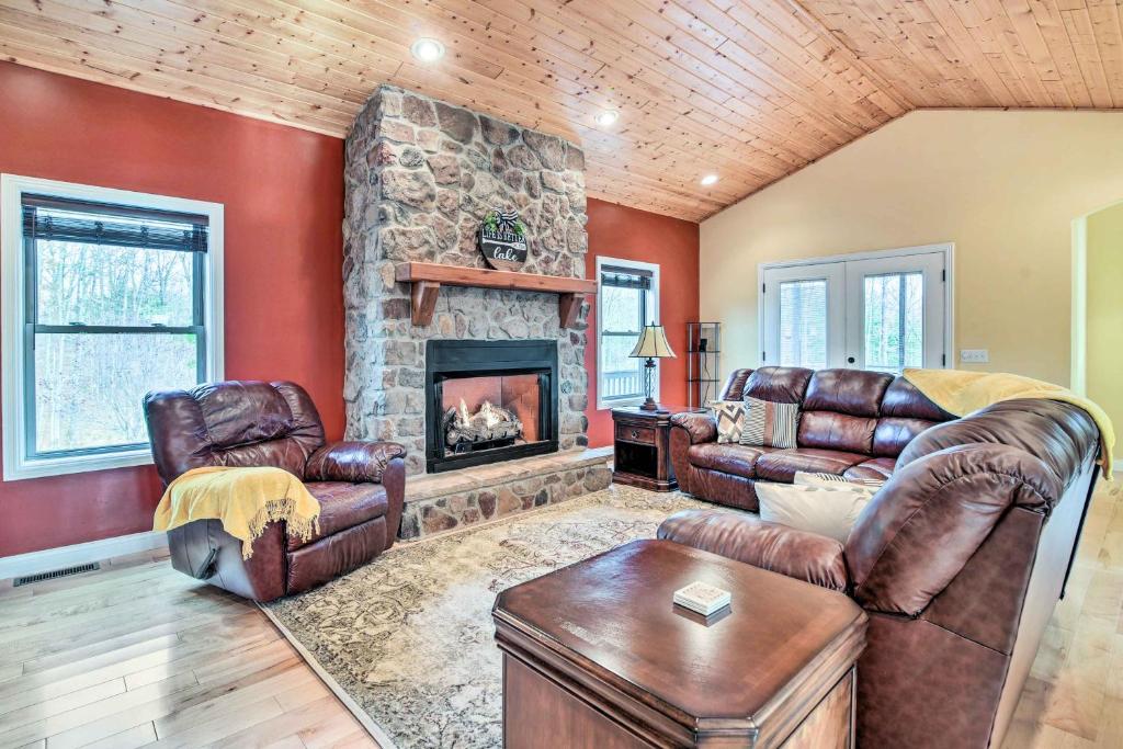 a living room with leather furniture and a stone fireplace at Cozy Home with Patio, 2 Mi to Dale Hollow Lake! in Frogue