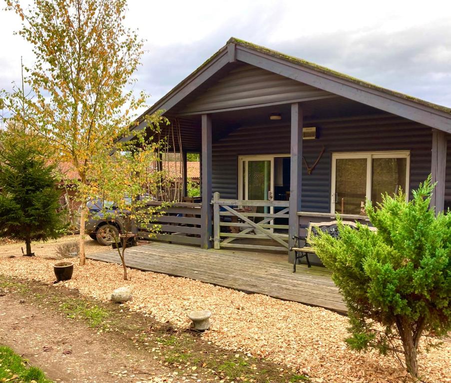 a small house with a porch and a wooden deck at Norfolk Cabin in Kings Lynn