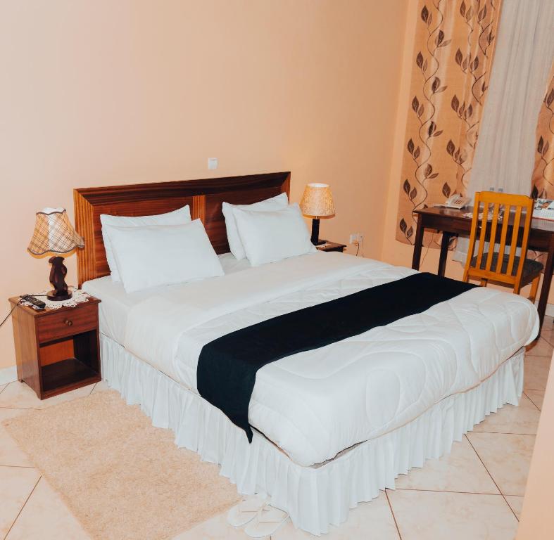 1 dormitorio con 1 cama grande, mesa y sillas en Centre Saint Vincent Pallotti en Kigali