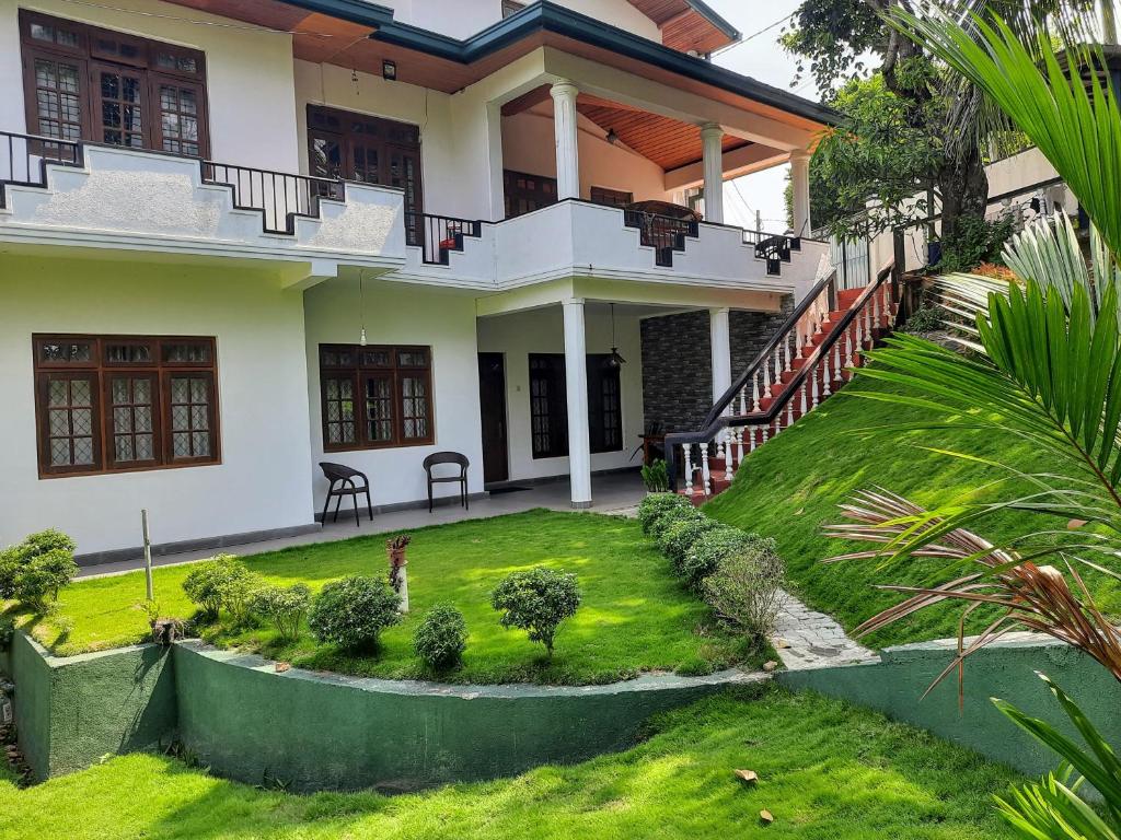 una casa con un césped verde delante de ella en Blue Ridge Homestay, en Kandy