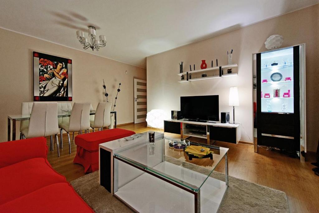 a living room with a red couch and a flat screen tv at Glamour Apartments Sopot in Sopot
