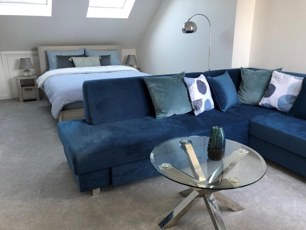 a living room with a blue couch and a bed at Ainslie Loft in Chingford, London in Chingford