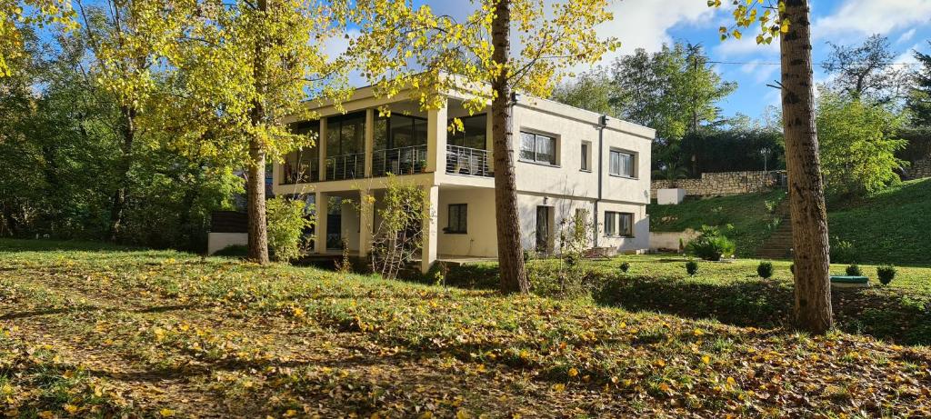 une maison blanche avec des arbres devant elle dans l'établissement T-2est 46m dons la maison au bord du Canal du Midi, à Saint-Hilaire-de-Lusignan